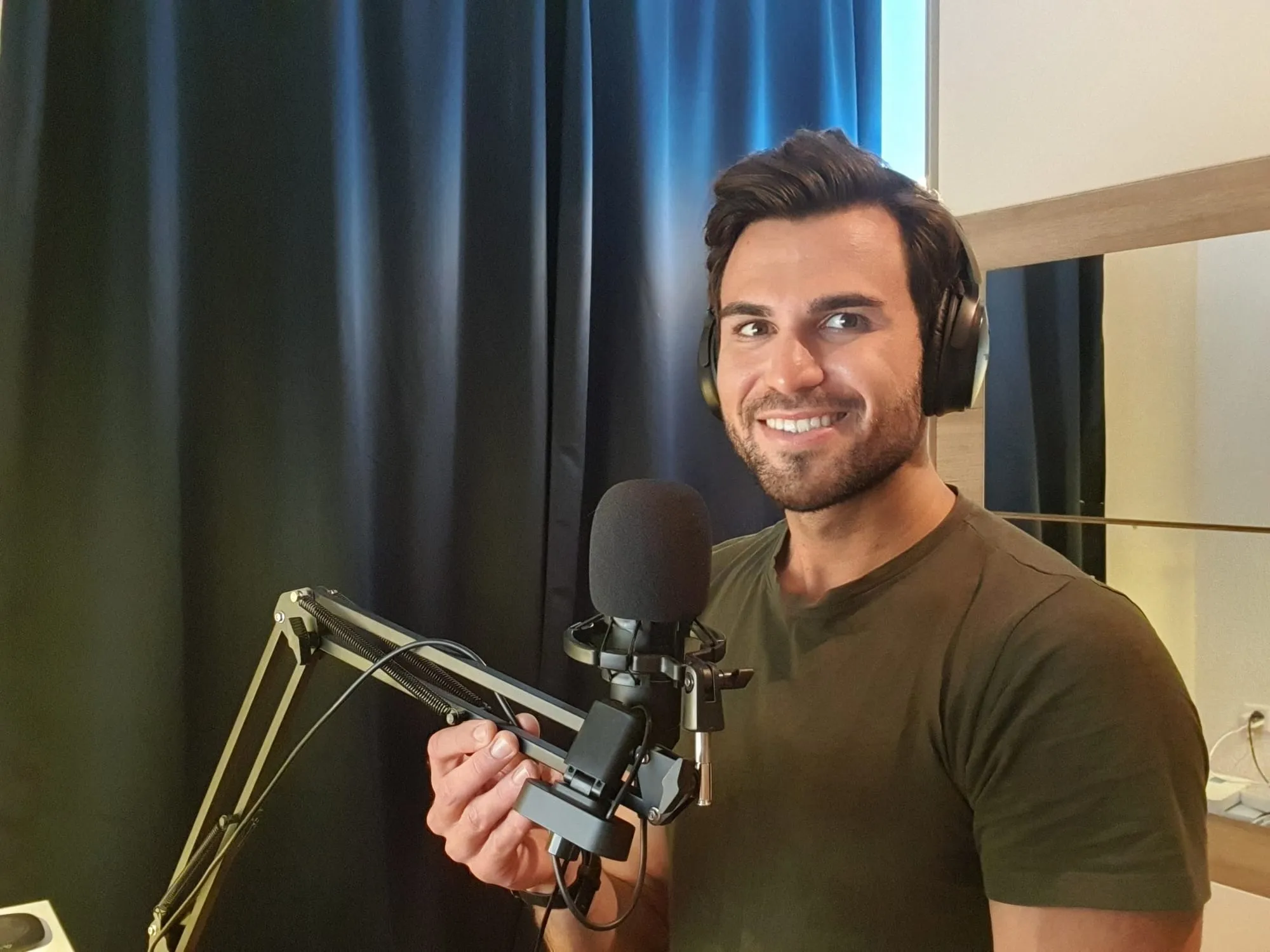 Lukas wearing headphones and speaking into a podcast microphone