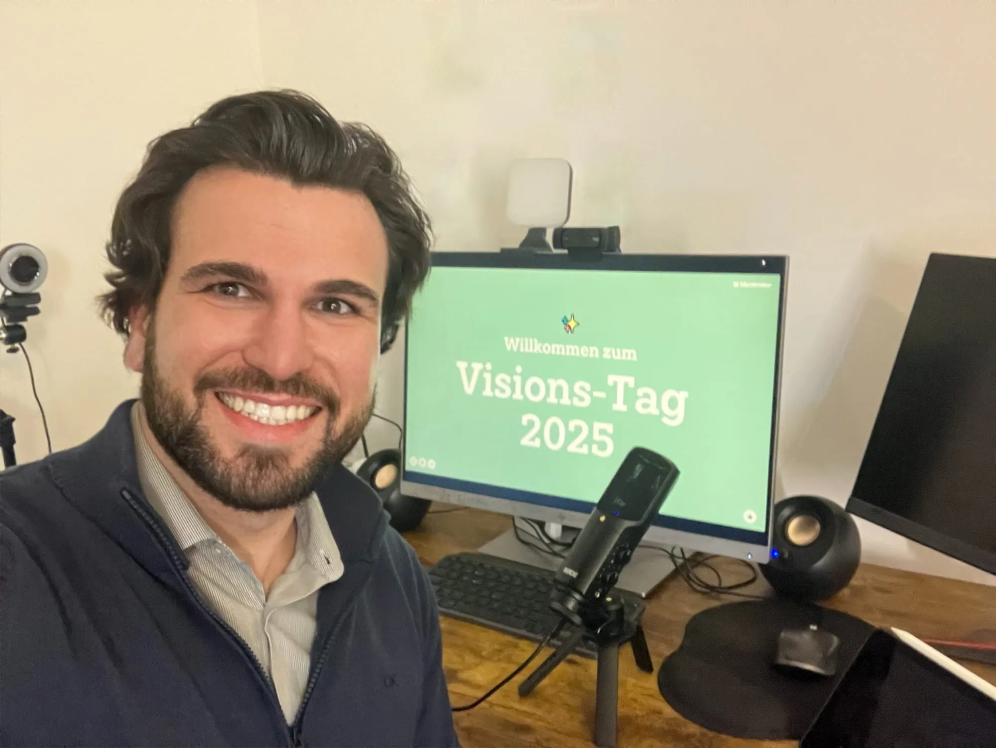 Lukas smiling next to a monitor showing Vision-Tag 2025