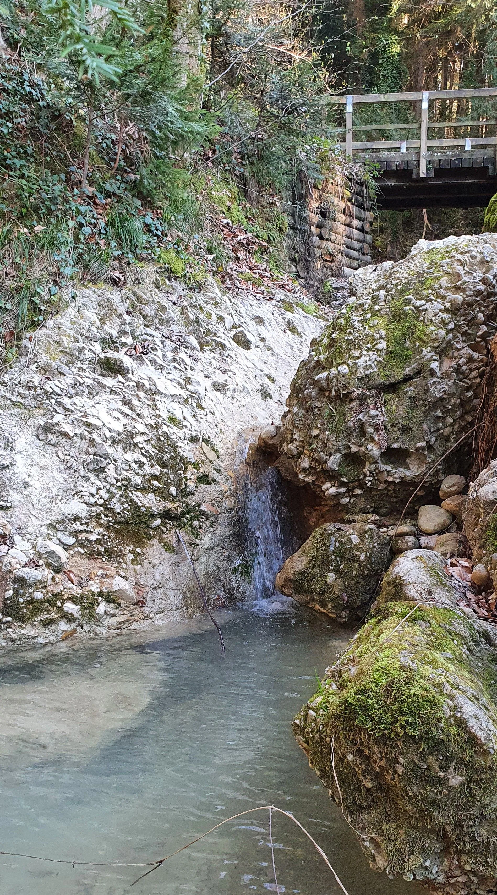 Clear mountain river with a small bridge and rocks
